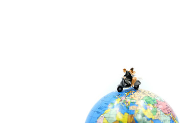 Miniature people : a newlywed couple riding the motorcycle on wolrd background for their honeymoon.