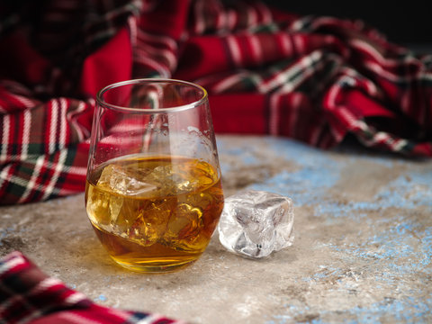 Still-life with a glass of bourbon. A glass of whiskey with ice. Concept of autumn spleen