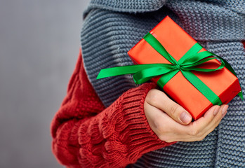 Female hand hold gift box on red sweater