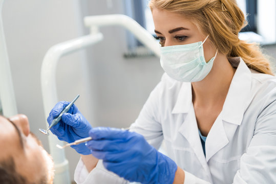 young female dentist examining teeth of client