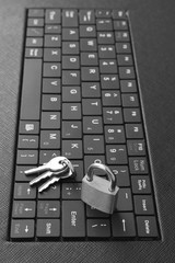 Locked padlock and keys on computer laptop or tablet keyboard. Black and white concept of internet password security, data privacy, cybercrime prevention. 