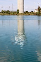 The tall water tower reflection off the water surface.