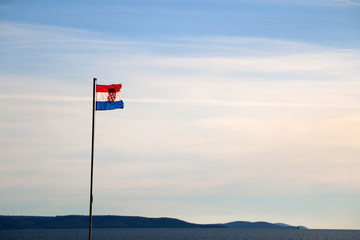 Flag of Croatia, blowing in the wind. Sky and sea in the background, selective focus. 