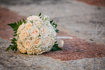 Bouquet da sposa composto di rose rosa, poggiato sopra la pietra
