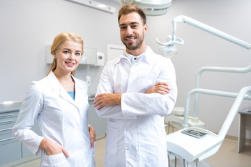 Fototapeta premium young male and female dentists looking at camera in dental office