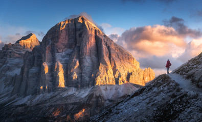 Young woman on the trail looking on high mountain peak at sunset in Dolomites, Italy. Autumn...