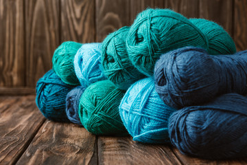 close up view of blue and green yarn clews on wooden surface