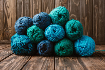 close up view of blue and green yarn clews on wooden surface