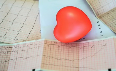 Cardiogram with small red heart on the table background. Top view, copy space