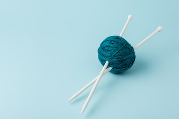 close up view of yarn ball and knitting needles on blue background