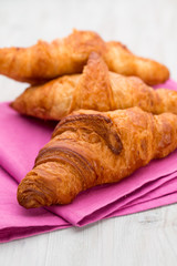 Tasty buttery croissants on old wooden table.