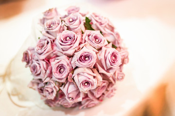 Bouquet da sposa realizzato con tante roselline color rosa sopra un tavolo bianco