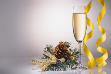 close up view of glass of champagne, christmas decoration and confetti on grey backdrop