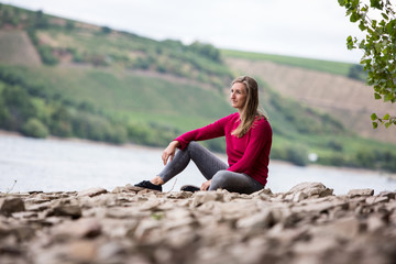 Junge Frau sitzt am Ufer eines Flusses
