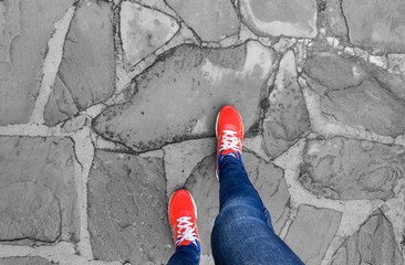 Legs in sneakers make a step on the pavement.