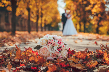 Wedding bouquet and wedding couple in orange park - obrazy, fototapety, plakaty