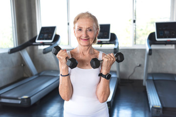Fototapeta na wymiar Senior woman exercise lifting dumbbell in fitness gym.