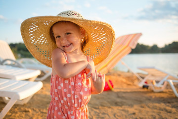 baby on the beach. girl Flirty on the background of sun loungers, sand and water. summer vacation...