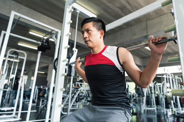 Fototapeta na wymiar Young asian man lifting barbell in gym. healthy lifestyle and workout motivation concept.