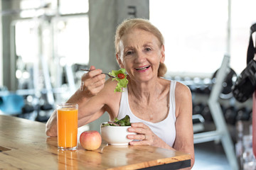 Senior woman eating healthy salad and orange juice. elderly health lifestyle concept.