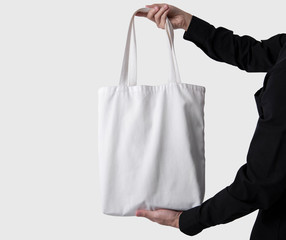 Man is holding bag canvas fabric for mockup blank template isolated on gray background.