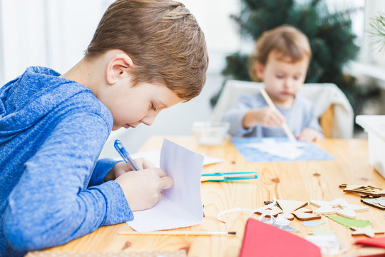 Boy and little girl preparing christmas cards for grandparents.