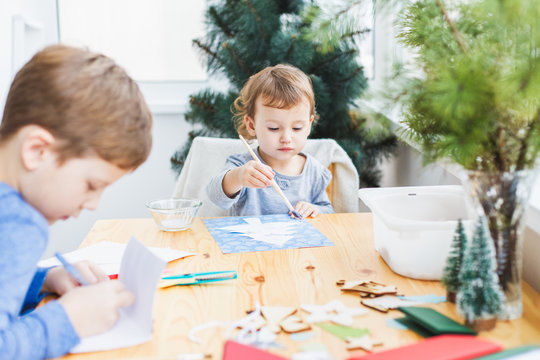 Boy and little girl preparing christmas cards for grandparents.