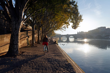 Sunrise and cyclist on the seine river quay in Paris - obrazy, fototapety, plakaty