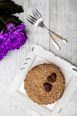 delicious sweet cake on wooden background with purple flowers flatlay