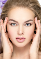 Fototapeta premium Beautiful young blonde woman with flowers near face