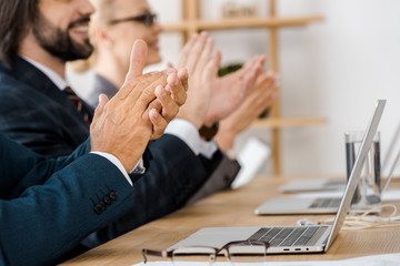 happy business people clapping hands at meeting in office