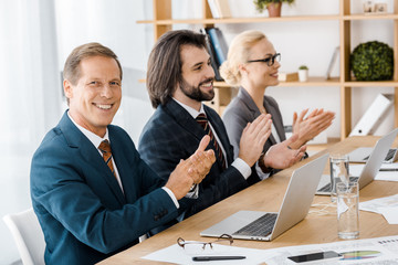 happy business people clapping hands at meeting in office