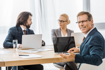 office workers sitting at table with laptops at meeting