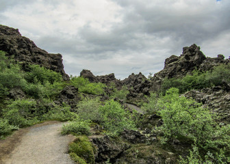 Fototapeta premium Dark lava rock formations area and green Icelandic forest in Myvatn area, Northern Iceland, Europe.