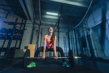 Athletic woman exercising with a barbell in the gym
