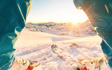 Legs view of skier athlete standing in front of wonderful sunset in ski resort
