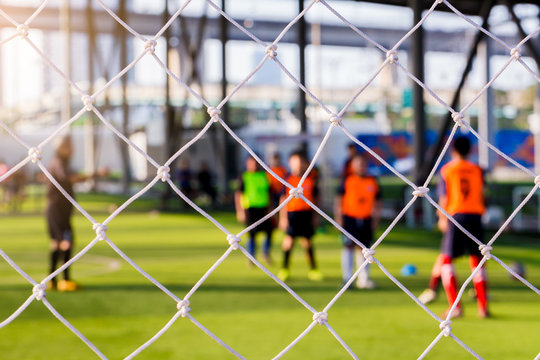 White Mesh Of Goal With Blurry Football Players.