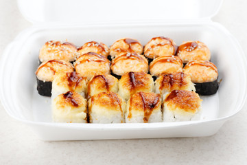 Sushi roll set in a white box. Hot baked rolls. Traditional Japanese food. Selective focus.