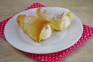 Delicious puff pastry cakes with protein cream on a white plate.