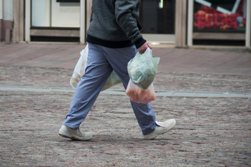 closeup of man walking in the street from the market with bags of fruits and vegetables