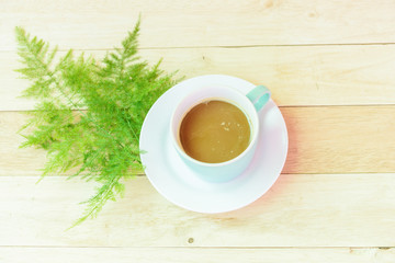 Hot coffee on wood plate with green leaf
