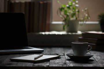 A cup of coffee in the workplace on a wooden table.