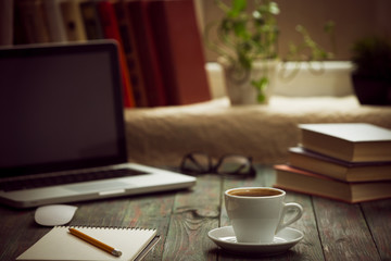 A cup of coffee in the workplace on a wooden table.