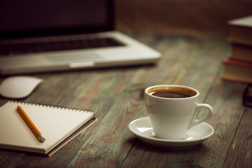 A cup of coffee in the workplace on a wooden table.