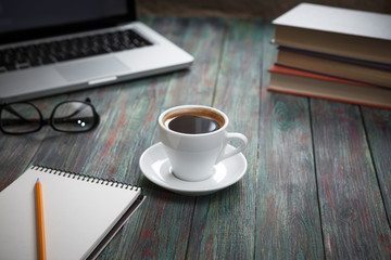 A cup of coffee in the workplace on a wooden table.
