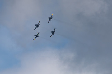 Low angle view of airshow in cloudy sky