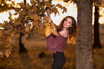 A portrait of a beautiful young woman in an autumn forest. Lifestyle, autumn fashion, beauty.