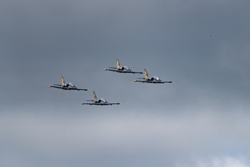 Low angle view of airshow in cloudy sky