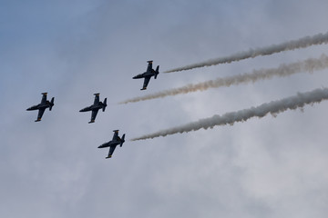 Low angle view of airshow in cloudy sky