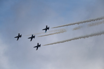 Low angle view of airshow in cloudy sky